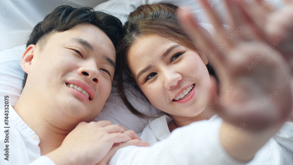 Top view young couple asia people lying down talk on bed relax smile hold hands look at ring on finger. Sweet happy lover asian man woman fall in true love new family life begin just married moment. Top view young couple asia people lying down talk on bed relax smile hold hands look at ring on finger. Sweet happy lover asian man woman fall in true love new family life begin just married moment.