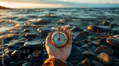 Hand holding a compass with a sea background