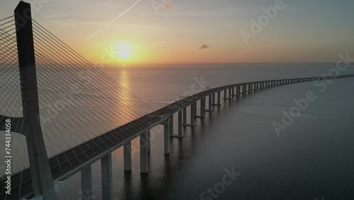 Drone flyover of Vasco da Gama bridge over Tagus river in Lisbon, Portugal at sunset on the hrozion photo