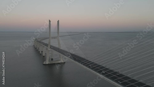 Drone flyover shot of Vasco da Gama bridge over Tagus river in Lisbon, Portugal at sunset photo