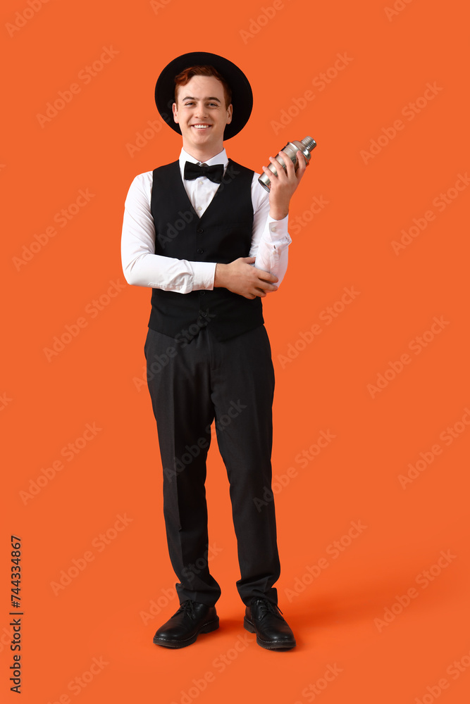 Obraz premium Young male bartender with shaker on orange background