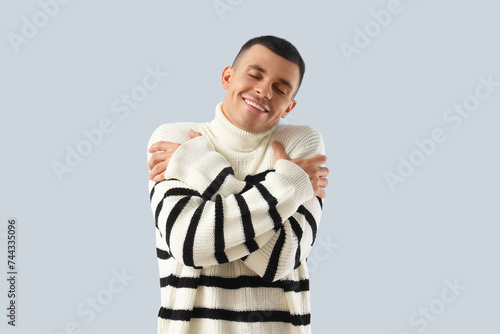 Young man hugging himself o...