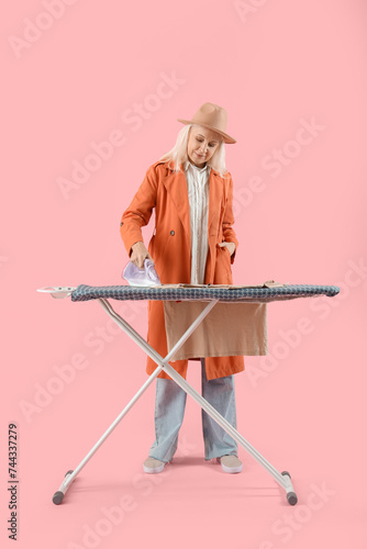 Happy mature woman ironing ...