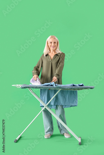 Happy mature woman ironing ...