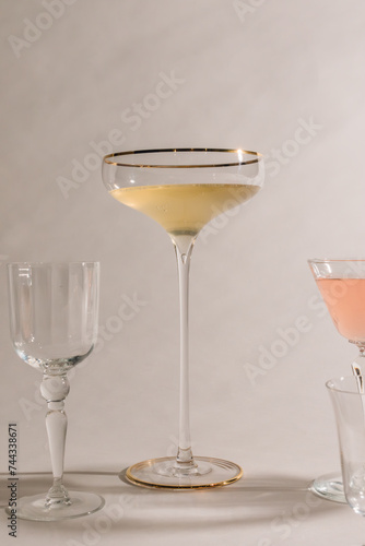 tall, thin stem champagne coupe with sherry, cocktail glasses against white with shadows 
