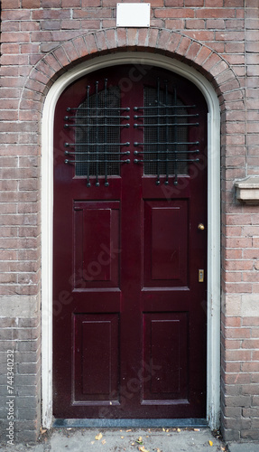 Traditional Red Door with Arched Frame on Brick Building © VGV