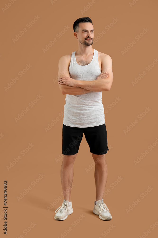 Handsome young happy man in sportswear on brown background Handsome young happy man in sportswear on brown background