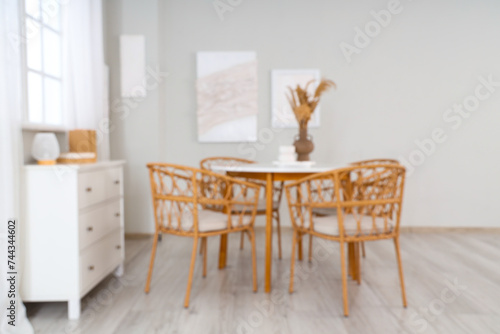 Blurred view of stylish dining room with paintings, drawers and table