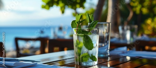 Refreshing glass of water with a fresh mint leaf on a wooden table photo