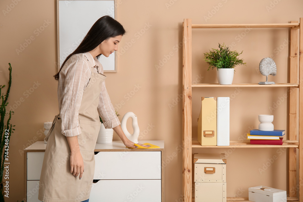 Fototapeta premium Young woman cleaning furniture in living room