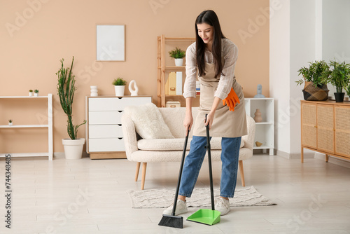 Young woman sweeping floor ...