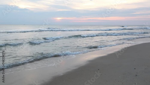 A scenic sunrise view of waves breaking along the shore of a beach in Nags Head, Outer Banks, North Carolina.