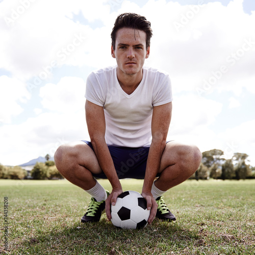 Man, soccer ball and portrait on ground for sports with pride, confidence and ready for challenge on field. Person, athlete and football player on grass for exercise, workout and training for game
