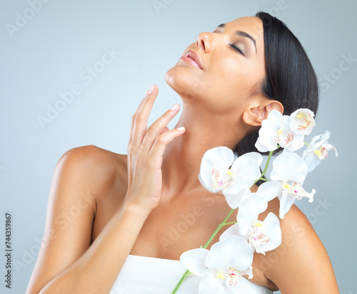 Flowers, skincare and woman with beauty, dermatology and person on a grey studio background. Model, luxury or girl with aesthetic or natural with facial or shine with glow and cosmetics with wellness