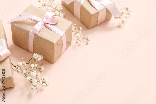 Cute wrapped gift boxes decorated with natural flowers on beige background