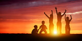Children's happy silhouettes at sunset. Group of funny kids are jumping in the meadow on a summer evening.