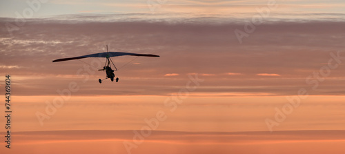 Hang glider on a motor on a summer evening against the backdrop of a sunset sky. Extreme sport. Banner, blank for an advertising layout with a place for writing © Alexandr Vasilyev