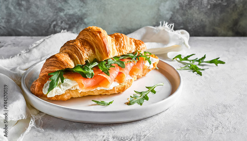 croissant sandwich, healthy breakfast. top view shot of Croissant sandwich with cream cheese, salmon and arugula on a white plate, copy space photo