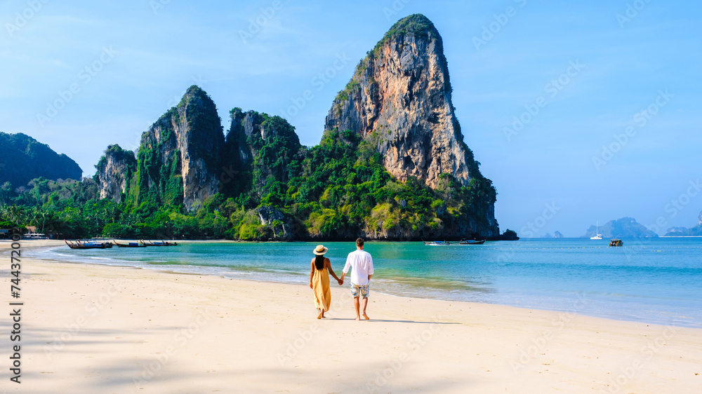 Obraz premium a couple of men and women relaxing on the beach during a vacation in Thailand Railay Beach Krabi with beautiful limestone cliffs in the background