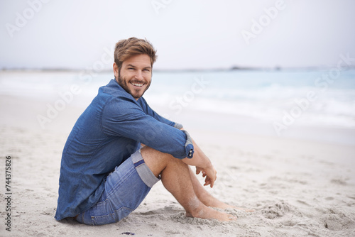 Portrait, beach and man with a smile, holiday and summer vacation with weekend break and water. Waves, face and person with happiness and guy with seaside and travel with journey or wind with nature