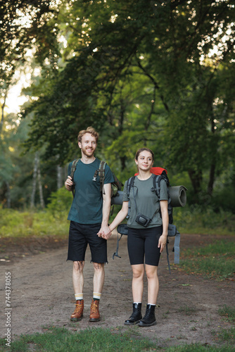 Photo of couple standing in forest at summer with a backpacks