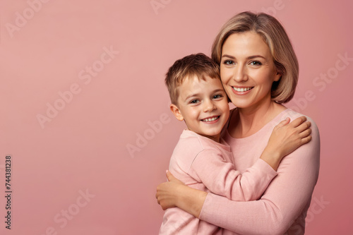 happy woman hug her son on pink background with copy space. Concept of Mothers day