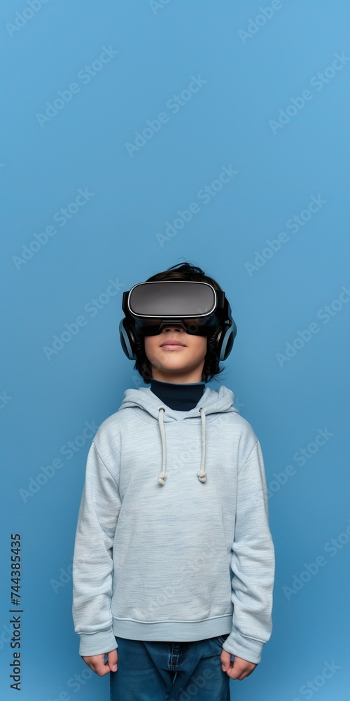 Hispanic or Mediterranean Kid Boy Wearing VR Headset, Enjoying Virtual Reality Experience on Blue Background with Studio Lighting. Vertical Photo Portrait (1:2) with Empty Copy Space Hispanic or Mediterranean Kid Boy Wearing VR Headset, Enjoying Virtual Reality Experience on Blue Background with Studio Lighting. Vertical Photo Portrait (1:2) with Empty Copy Space