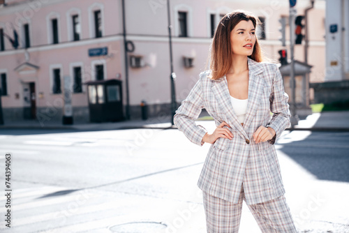 Portrait of young beautiful brunette woman wearing nice trendy plaid suit jacket. Sexy smiling model posing in the street at sunny day. Fashionable female outdoors. Cheerful and happy. © halayalex