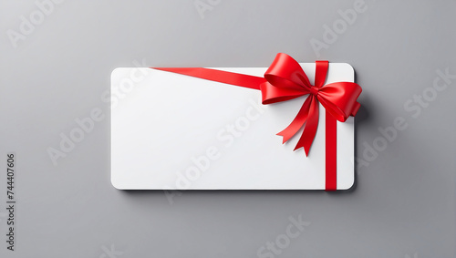 Blank white gift card with red ribbon bow isolated on grey background with shadow minimal conceptual