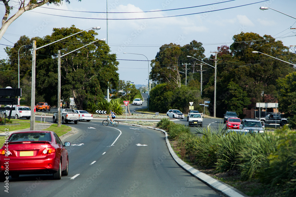 Cars and cyclist approaching a large roundabout in heavy traffic Cars and cyclist approaching a large roundabout in heavy traffic