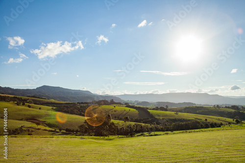 Beautiful green hills with sun flare shining over landscape photo