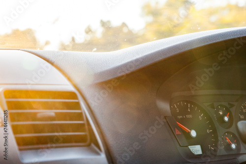 Golden sun flare over air con vent and speedometer of car photo