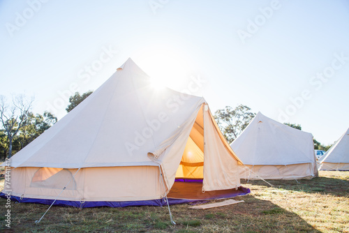 Sun flare over old fasioned white tent with open flaps in the morning photo