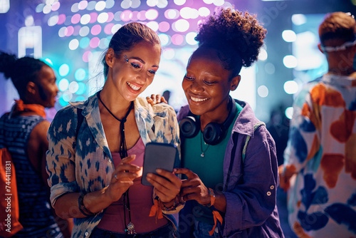 Sticker Happy female friends using cell phone during summer music festival at night
