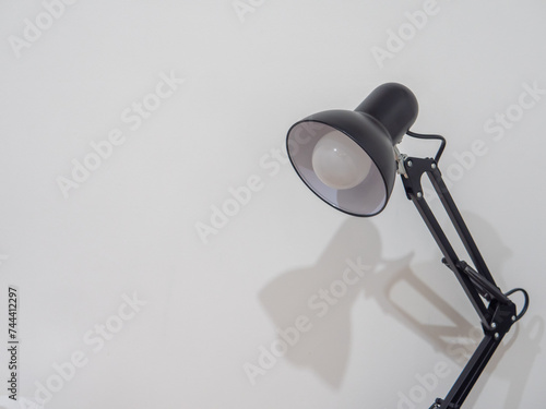 Black lamp behind a white background. © phuangphech