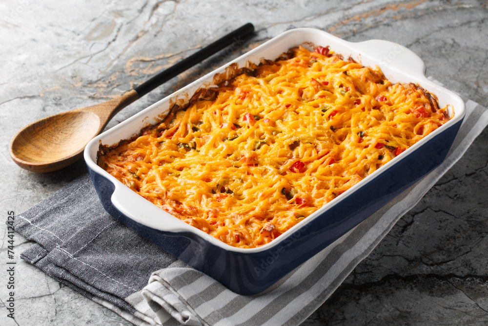 King Ranch Casserole layers of juicy chicken, corn tortillas and cheese enveloped in a cream sauce with tomatoes, bell peppers and green chiles close-up in a baking dish on a marble table. Horizontal