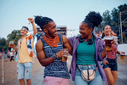 Cheerful black couple drinking beer and having fun on open air music festival in summer.