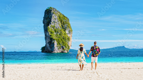 Diverse couple of Asian women and European men walking on the tropical beach of Koh Poda Island Krabi Thailand. Beautiful tropical beach in Thailand with a limestone cliff island in front, rear view © Fokke Baarssen