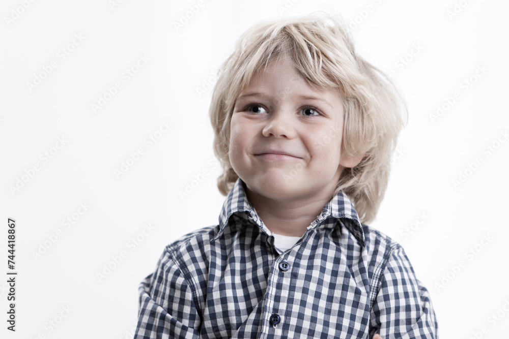 A smiling young boy looking to side on a white background A smiling young boy looking to side on a white background