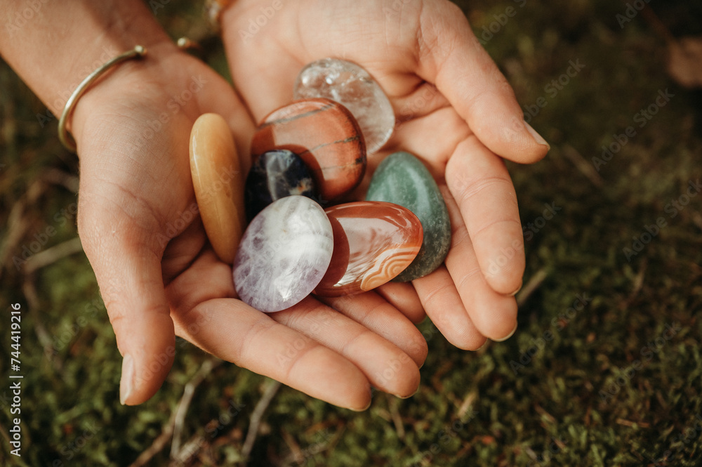 Woman hands holding healing gem stones on green moss Woman hands holding healing gem stones on green moss