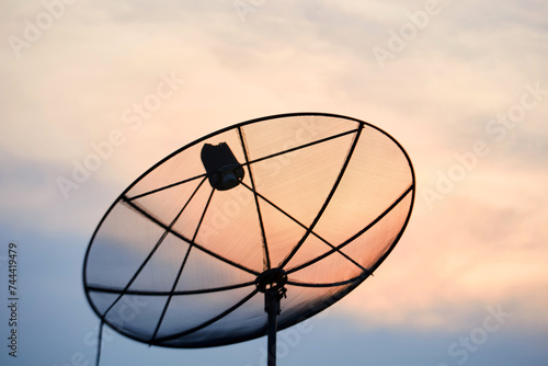Silhouette of satellite dish antenna against sunset