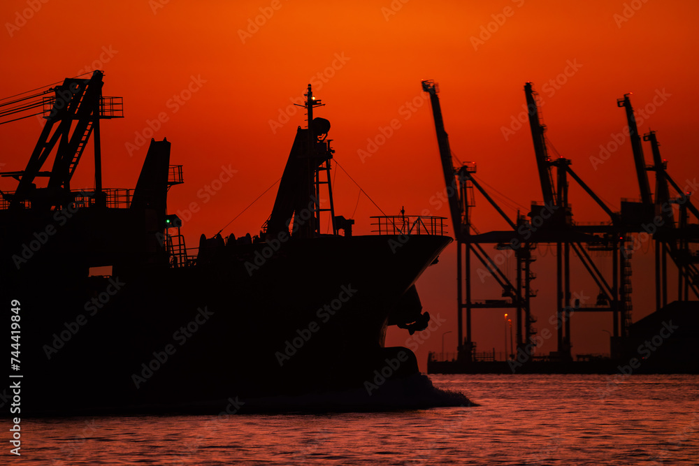Obraz premium 関門海峡の朝焼けの中のガントリークレーンと貨物船のシルエット20240218-2