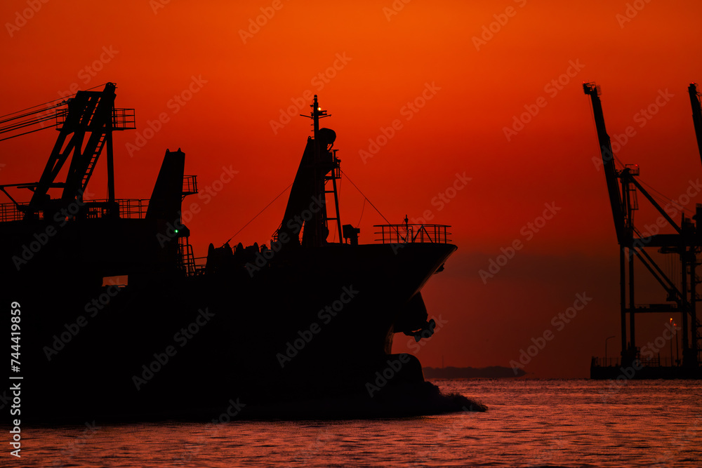 関門海峡の朝焼けの中のガントリークレーンと貨物船のシルエット20240218-1