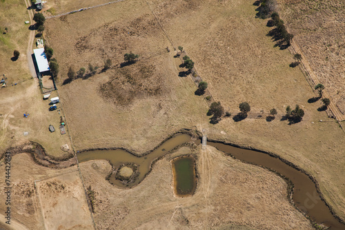 Overhead view of dry paddocks of brown farmland with river and dam photo