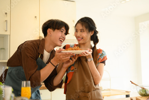 Wallpaper Mural Happy Asian couple holding plate of spaghetti, cooking in kitchen together on weekend Torontodigital.ca