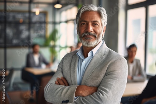 Confident middle aged Indian businessman manager standing at office team meeting. Portrait of elegant smiling professional senior male company executive leader crossing arms in board, Generative AI photo