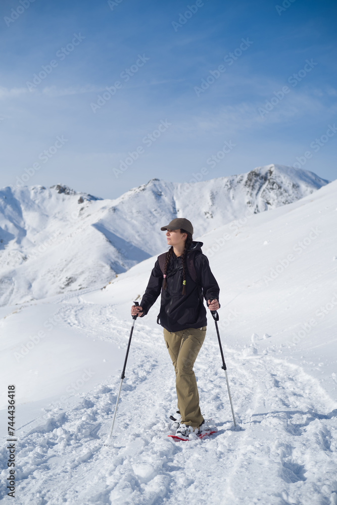 Chica caminando por la nieve con raquetas de nieve y bastones en la alta montaña en un día soleado Chica caminando por la nieve con raquetas de nieve y bastones en la alta montaña en un día soleado