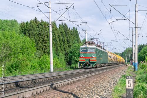 The train is moving along the railway tracks. The tank car is pulled by two electric locomotives. Transportation of petroleum products by rail. Wagons with liquefied gas.
