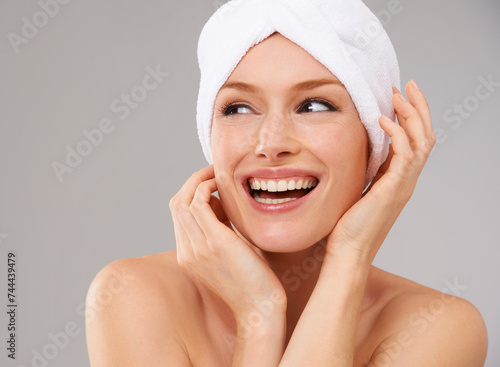 Happy, woman and thinking about skincare for beauty and healthy dermatology in studio background. Girl, smile and model laughing with glow on skin from facial, cosmetics or towel for self care
