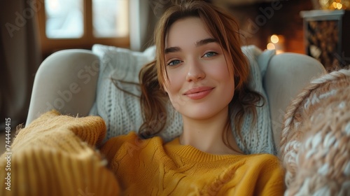 A contented young woman sits on a sofa at home, gazing at the camera